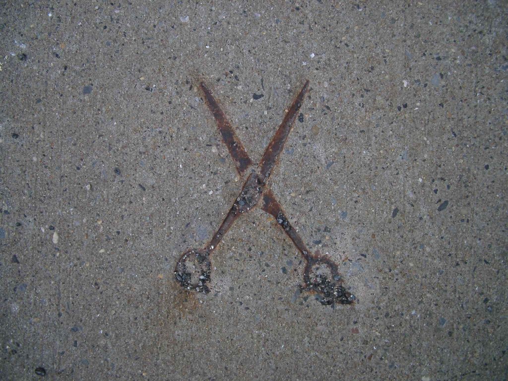 Old rusty scissors in the sidewalk